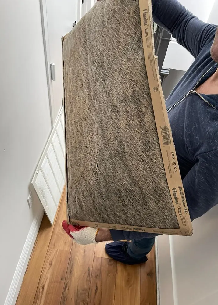Hands replacing a home HVAC air filter